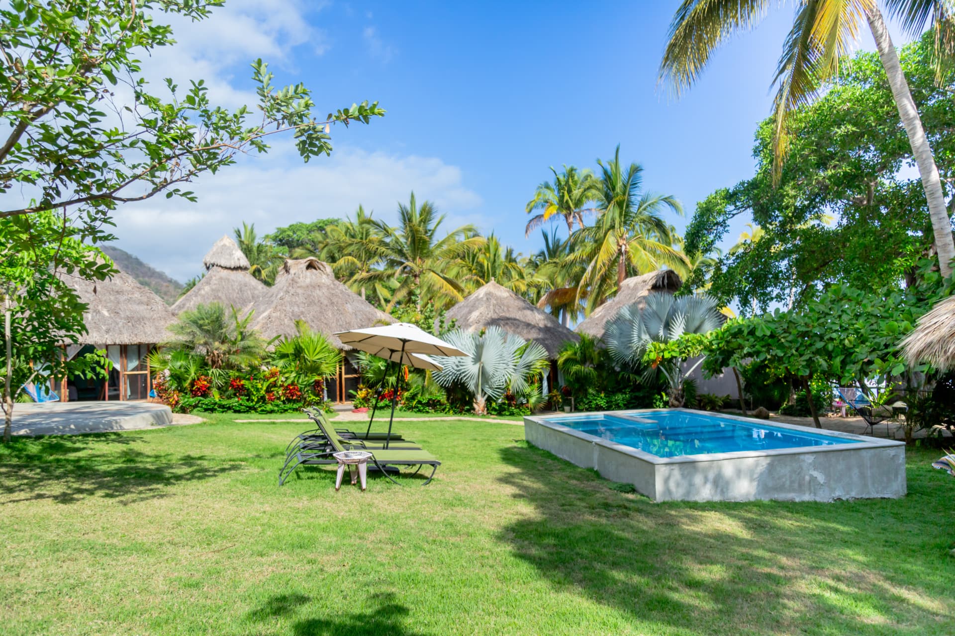 Garden with loungers, umbrella and pool under a blue sky