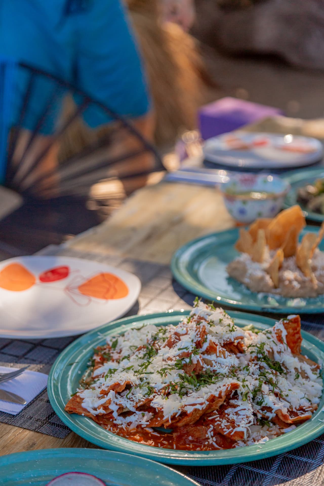 Red chilaquiles with cheese and cream served on a turquoise plate