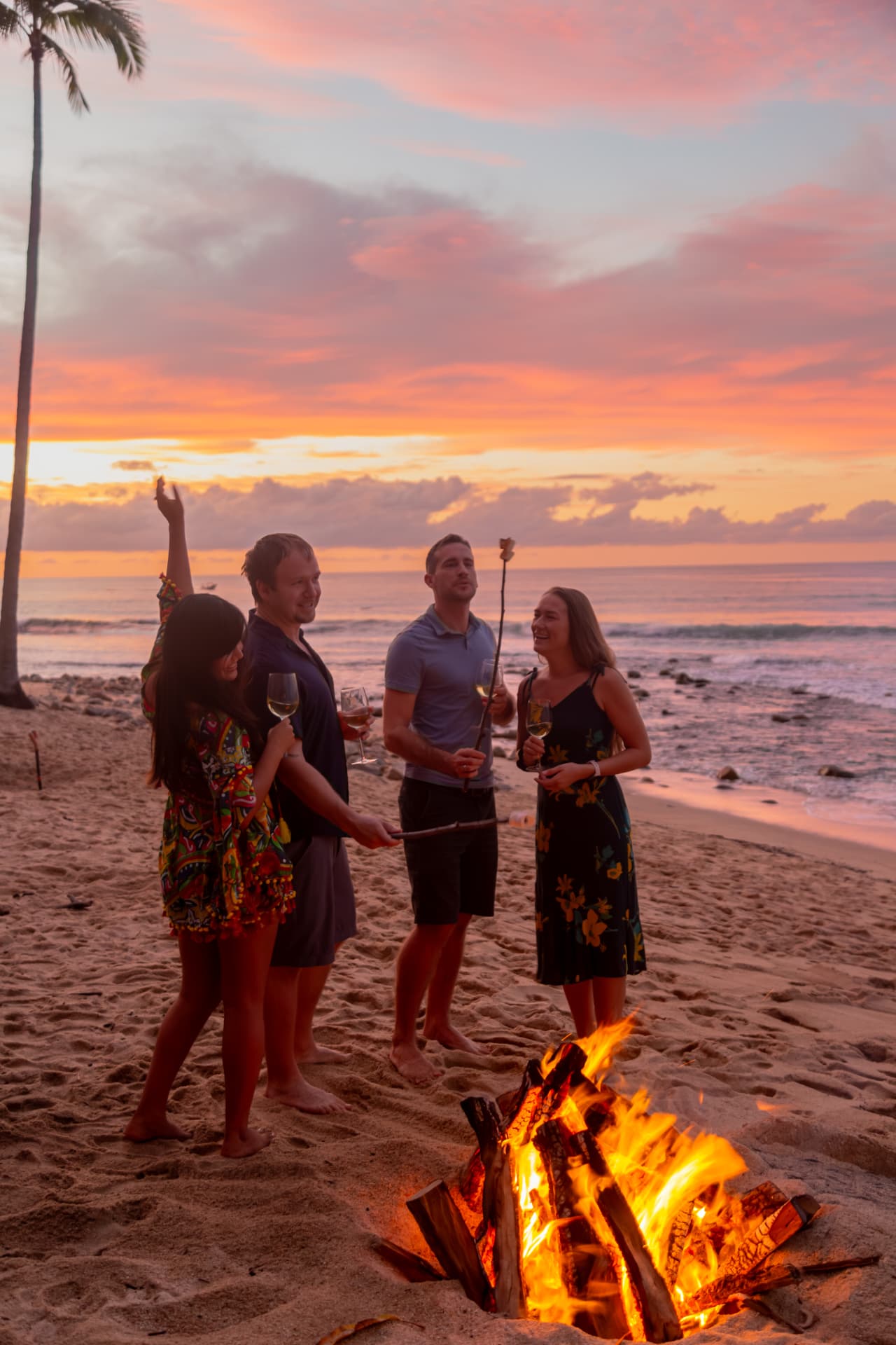 Friends roasting marshmallows at the beach bonfire at dusk