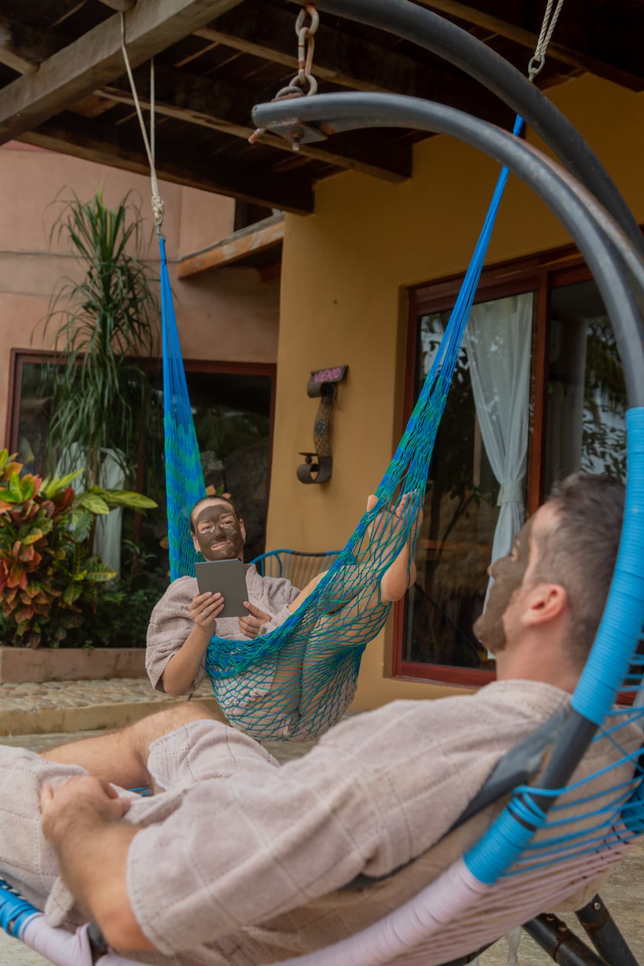 Guests resting in hanging hammocks with clay masks on