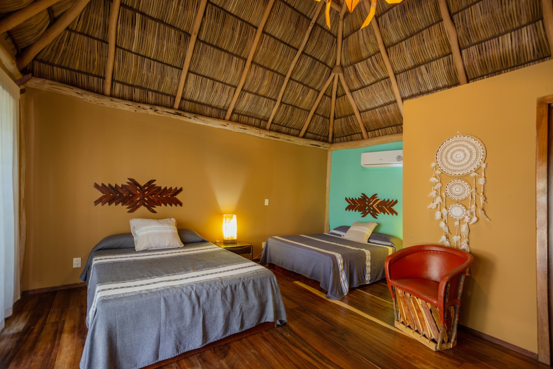 Palapa Suite: dos camas dobles bajo el techo de palapa con muro turquesa
