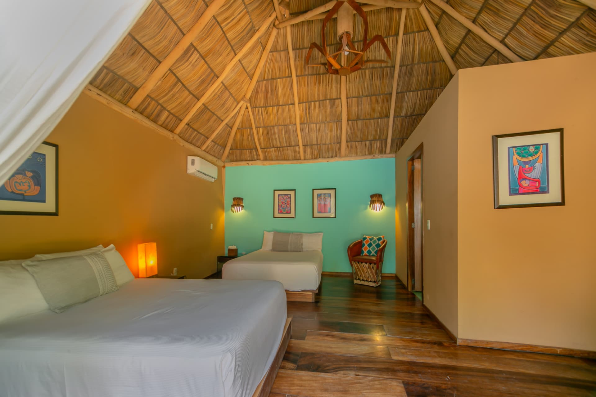 Palapa Suite con techo de palapa, dos camas y muros de colores