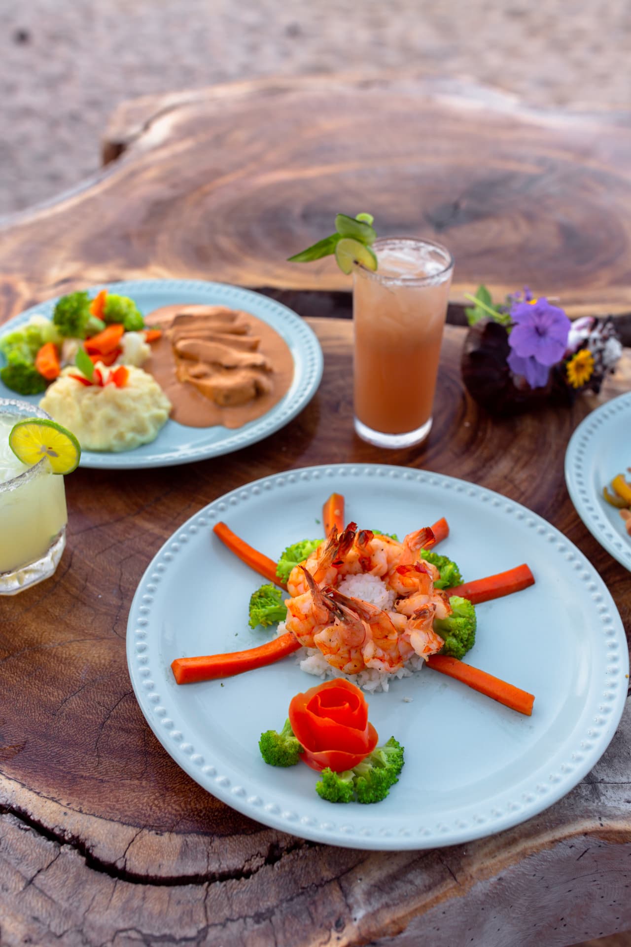 Plate of shrimp with rice and vegetables on a parota wood table