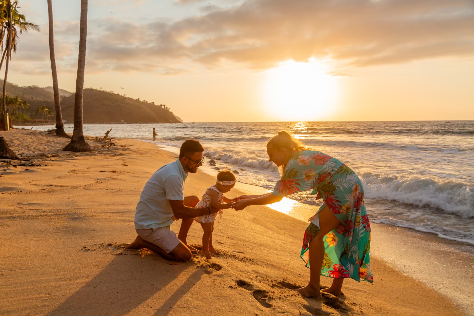 Family playing with their baby at the shoreline at sunset