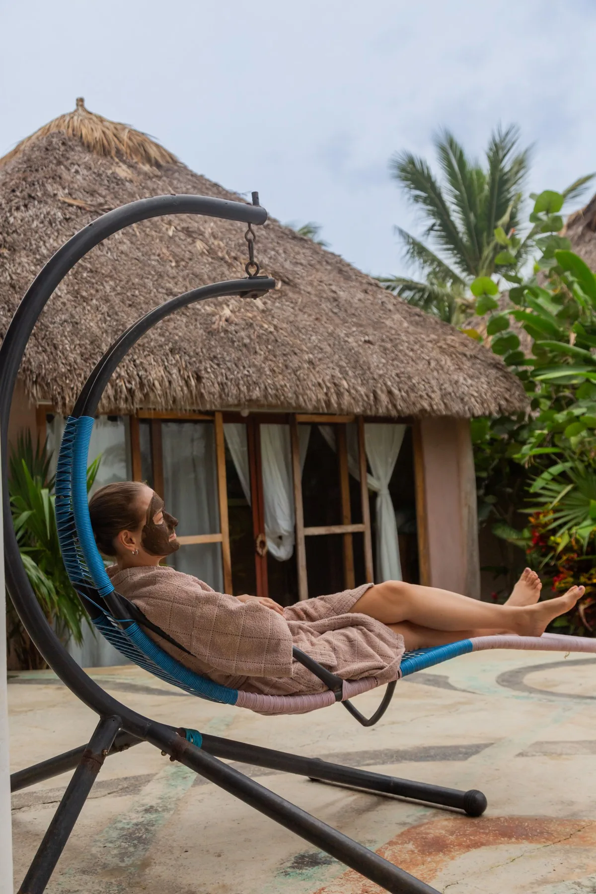 Resting on a hanging chair in front of tropical rooms